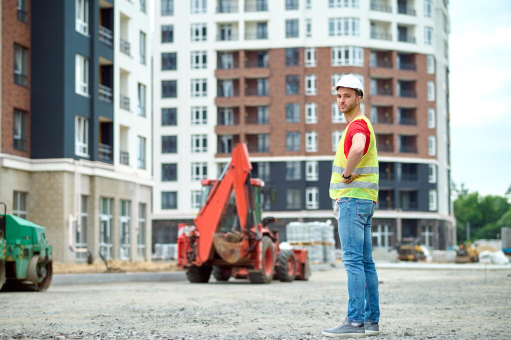 Trust Patrick's worker in a reflective vest and a hard hat standing on a construction site.