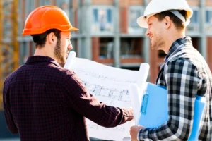 Trust Patrick's workers in hard hats discuss blueprints at a building site.